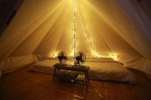 a bedroom with a bed in a tent with lights at ปิติฟาร์มมิลี่ คาเฟ่&แกลมปิ้ง ผามออีแดง in Ban Phumsaron