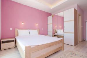 a bedroom with a large bed and a pink wall at Pool Villa Panorama Mojdež - Happy Rentals in Igalo +18 photos