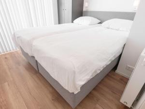 a bed in a bedroom with white sheets and pillows at House in Zeeland near the Dyke in Wemeldinge