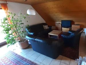 a living room with a black leather couch and a table at Holiday apartment Renate in Rottenburg