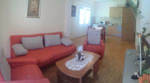 a living room with a red couch and a table at Gjole Apartments in Lagadin