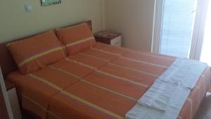 a bedroom with a large bed with orange sheets at Gjole Apartments in Lagadin