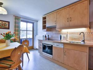 uma cozinha com armários de madeira, uma mesa e uma sala de jantar em Haus Brandl Modern retreat em Ramsau