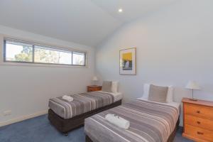 a bedroom with two beds and a dresser and a window at Banjo's Way 2 in Jindabyne