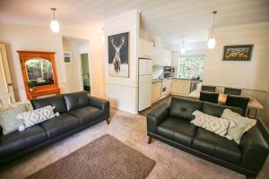 a living room with two black leather couches and a kitchen at Silver Birches Holiday Village - Unit 8 in Bright