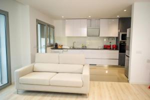 a white couch in a living room with a kitchen at Batalha - Ferreiras Apartment in Batalha