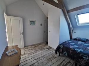 a bedroom with a bed and a wooden floor at Le p'tit coin dans les vignes in Restigné