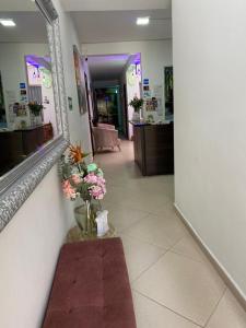 un corridoio con specchio e vaso di fiori di Hotel House a Medellín