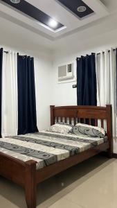 Bett in einem Zimmer mit blauen Vorhängen in der Unterkunft Amanda's Ridge Home in Tagaytay