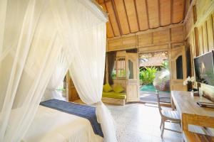 a bedroom with a canopy bed with a desk at Royal Casa Ganesha in Ubud