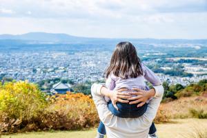 a man holding a child on top of a hill at ANDO HOTEL NARA Wakakusayama -DLIGHT LIFE & HOTELS- in Nara