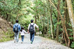 a family walking down a path in the woods at ANDO HOTEL NARA Wakakusayama -DLIGHT LIFE & HOTELS- in Nara