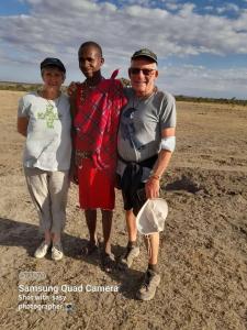 a group of three people standing in a field at D-TURA Guest House in Sekenani