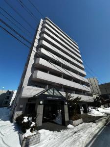 een hoog gebouw met sneeuw ervoor bij 9-5 NEW OPEN　美室駅近で眺望良好　駐車場予約可 in Minami-jūichijō