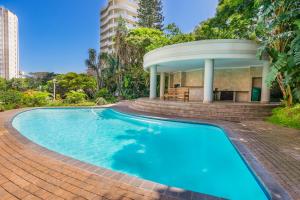 a swimming pool with a gazebo next to a building at 603 Oyster Rock Umhlanga Rocks in Durban