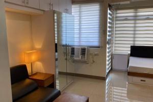 ein Wohnzimmer mit einem Fenster mit einem Bett und einem Stuhl in der Unterkunft Mabolo Garden Flat A10 Free pool Near Ayala Mall in Cebu City
