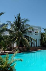 a building with palm trees in front of a swimming pool at Mwezi Nyota in Malindi