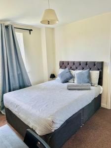 a bedroom with a large bed with blue pillows at DARTFORD CROSSING The BRIDGE PLACE - CONTRACTORS FAVOURITE in Kent