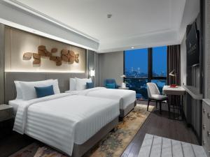 a hotel room with two beds and a desk at Royal Malioboro by ASTON in Yogyakarta
