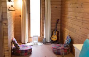 una habitación con 2 sillas y una guitarra en la pared en Krishna Farm Retreat en Coolabine