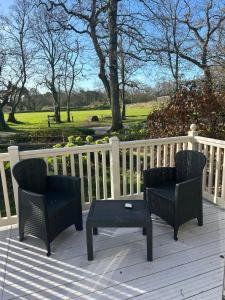 two chairs and a table on a deck with a fence at New Forest 2-Bed Premium Holiday Home, Hoburne Bashley Holiday Park, New Milton in New Milton