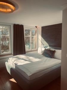 a bedroom with a large bed and two windows at Boutique Hotel Bellevue B&B am Brienzersee Iseltwald Interlaken in Iseltwald