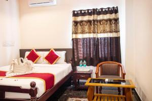 une chambre d'hôtel avec deux lits et une chaise dans l'établissement MUTHU RESIDENCY, à Thanjavur