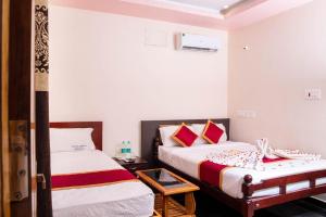 Cette chambre comprend 2 lits avec des murs blancs et des oreillers rouges. dans l'établissement MUTHU RESIDENCY, à Thanjavur