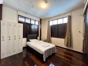 a bedroom with a bed and two windows at Allred Hostel Chiangmai in Chiang Mai