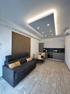 a living room with a black couch and a kitchen at Coho House Fiumicino in Fiumicino