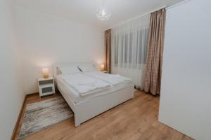 a white bedroom with a bed and a window at CityVibe Residence in Târgu-Mureş