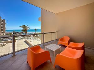 balcón con sillas de color naranja y vistas a la playa en Luxury Ocean View Condo w Huge Deck, en Puerto Peñasco