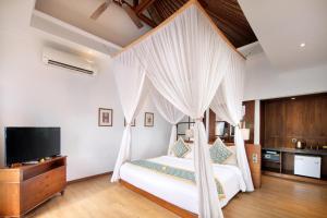 a bedroom with a bed with curtains and a television at Lembongan Beach Club & Resort in Nusa Lembongan
