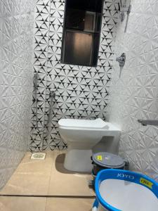 a bathroom with a toilet and a window on the wall at Backpackers Villa Mumbai in Mumbai