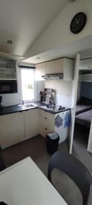 una pequeña cocina con fregadero y un reloj en la pared en Mobil Home 3 chambres, en Ouistreham