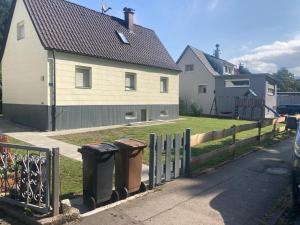 ein Haus mit zwei Mülltonnen neben einem Zaun in der Unterkunft HummelHaus 3 in Lindau in Lindau