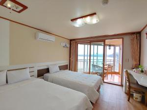 a bedroom with two beds and a desk and a balcony at Bomulsum in Seogwipo