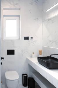 La salle de bains blanche est pourvue d'un lavabo et de toilettes. dans l'établissement Villa Sea Queen, à Novalja