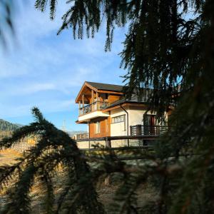 a house is seen through the branches of a tree at Chalet Deluț in Suceava