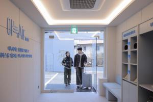 um homem e uma mulher a andar por um corredor com a sua bagagem em Aank Air Hotel Daejeon em Geochang