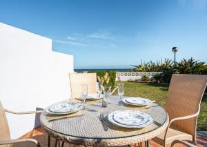 un tavolo con piatti e bicchieri su un patio di 3 Front Line Beach house Playa Paraiso Manilva a Manilva