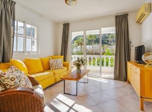 un soggiorno con divano giallo e TV di 3 Front Line Beach house Playa Paraiso Manilva a Manilva