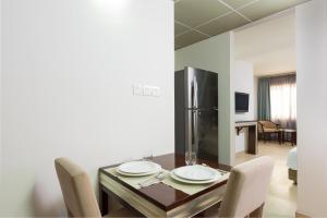 Centara Life Muscat Dunes Hotel في مسقط: غرفة طعام مع طاولة مع كراسي وثلاجة