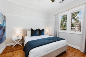a white bedroom with a large bed and two windows at 'The Nicholson' A Central and Charming Cottage in Mudgee in Mudgee