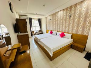 a bedroom with a large bed with pink pillows at REDFLOWER HOTEL in Ho Chi Minh City