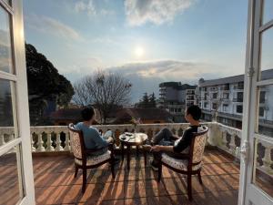 zwei Männer sitzen um einen Tisch auf dem Balkon in der Unterkunft Vintage Villa Sapa in Sa Pa