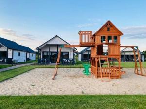 a playground with a tree house and a swing at Storey holiday cottages, Jaros awiec in Jarosławiec