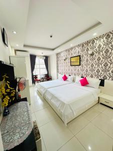a bedroom with a large white bed with pink pillows at REDFLOWER HOTEL in Ho Chi Minh City