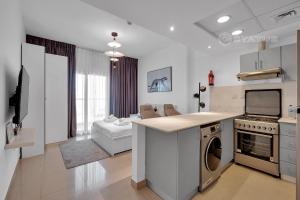 a kitchen and living room with a stove and a dishwasher at Sleek Studio - Red Residence-L8 - Near ISD Stadium in Dubai