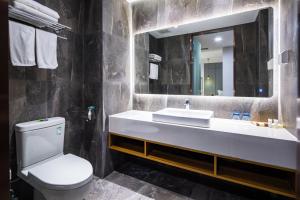 a bathroom with a sink and a toilet and a mirror at Qingdao Villa Inn in Qingdao